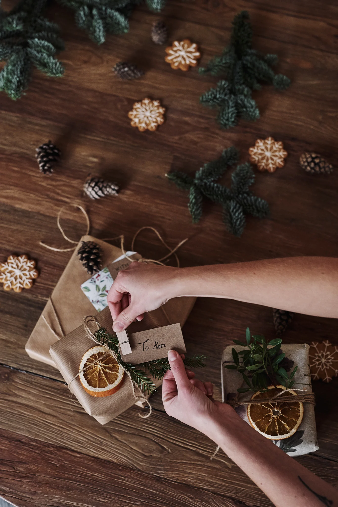 Geschenke gehören natürlich ebenfalls zu Weihnachten in Schweden. Hier liegen verpackte Geschenke und ein paar Hände pinnt ein Namensschild daran.