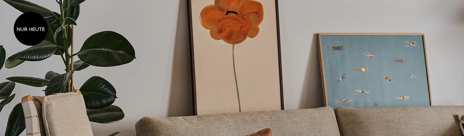 Ein Wohnzimmer mit einer Pflanze, zwei Kunstwerken, die ein orangefarbenes Mohn und schwimmende Menschen zeigen, und einem Sofa.