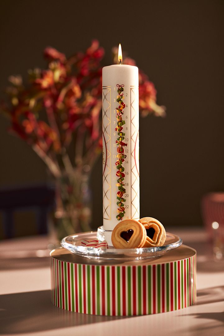 Die Adventskerze von Holmegaard steht auf einer weihnachtlichen Schachtel, zusammen mit Keksen.