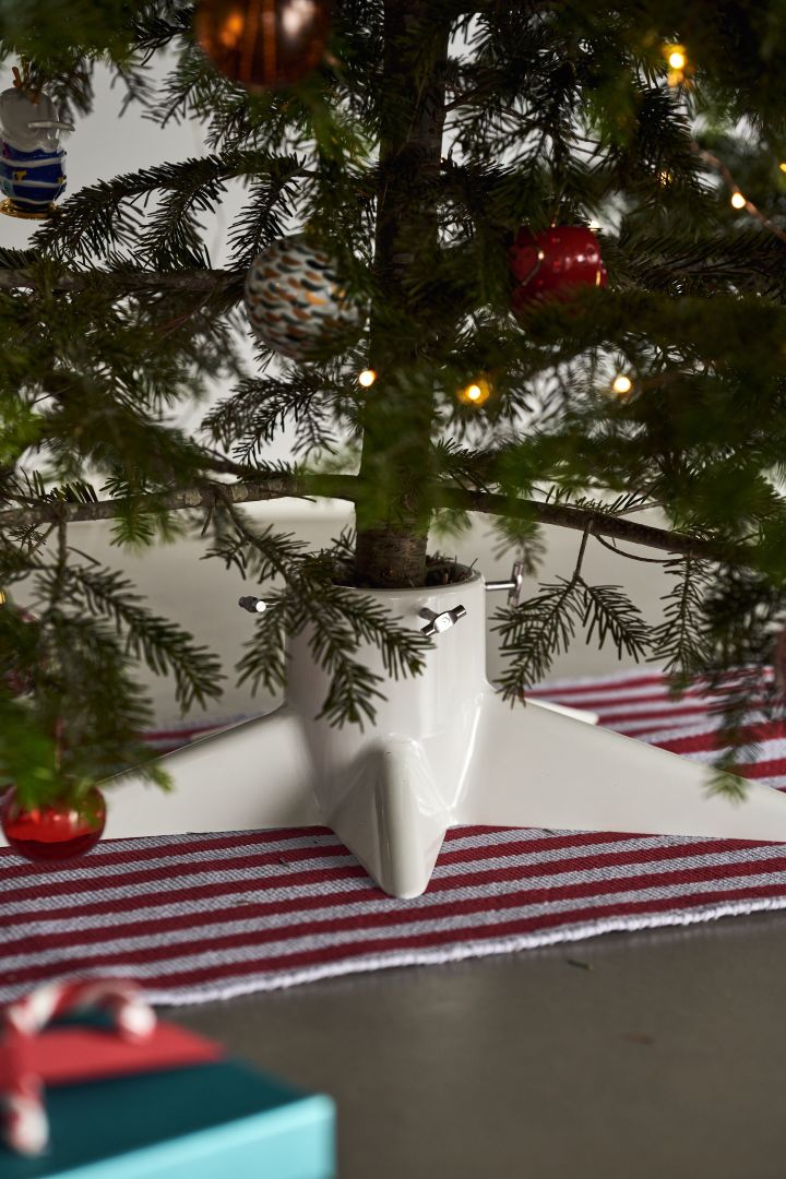 Dekorieren Sie Ihren Baum dieses Jahr mit dem Weihnachtsbaumschmuck 2021 in den 4 verschiedenen Stilen der Nest Trends – Nurture, Share, Boost und Cultivate. Hier sehen Sie einen rot-weiß gestreiften Teppich von HAY und einen weißen Weihnachtsbaumfuß von Born in Sweden.