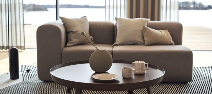 Richten Sie Ihr Wohnzimmer mit beigen Möbeln ein, um einen beruhigenden Raum und ein Zuhause zum Wohlfühlen zu schaffen. Hier sehen Sie beige Kissen von Ernst, Lines Porzellan von NJRD und Pastille Vase von Cooee Design auf dem Around Couchtisch von Muuto.