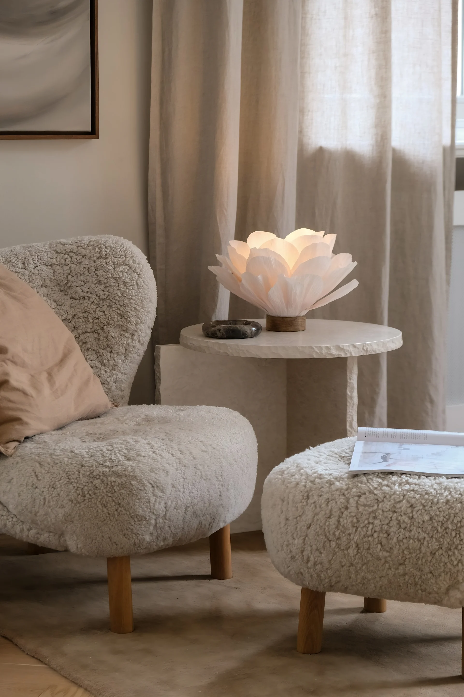 Ein beigefarben eingerichtetes Wohnzimmer mit einem Little Petra Sessel und einem marmornen Couchtisch, dekoriert mit der Lisa Tischlampe von Watt & Veke.