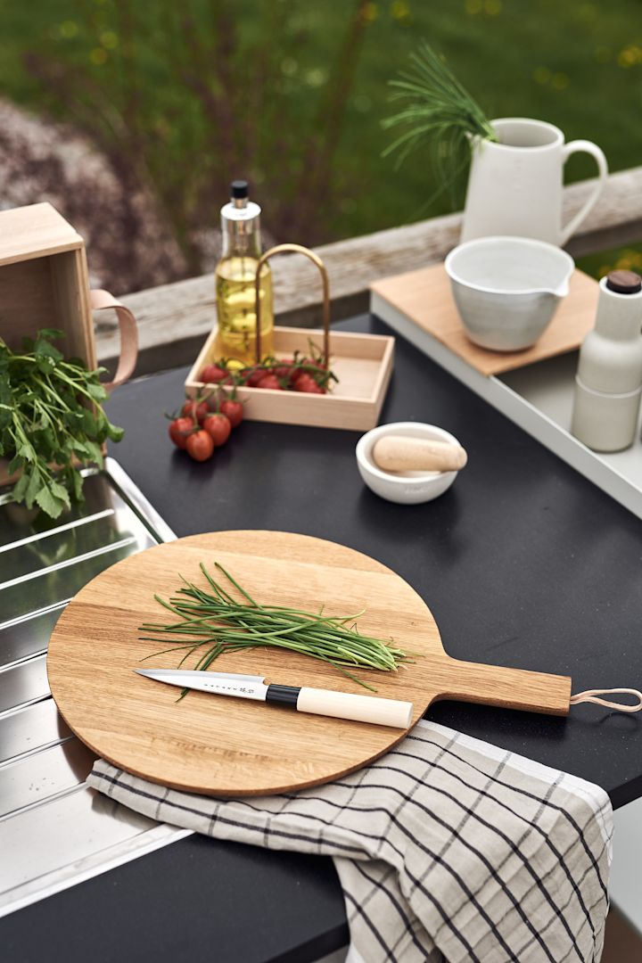 So organisieren Sie ein Grillfest – hier das Satake Houcho Filiermesser, das Nordic Kitchen Holzschneidebrett von Eva Solo und das Hale Geschirrtuch von Ferm Living.