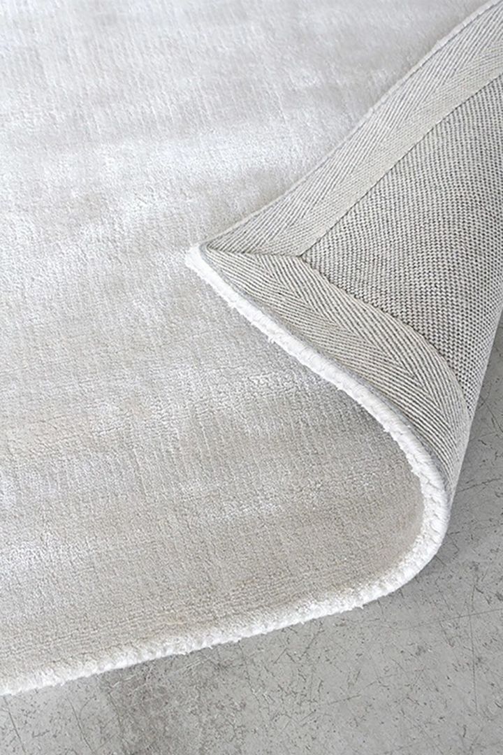 Nahaufnahme des Teppichs aus fester Viskose in Francis pearl beige von Layered, der Ihrem Zuhause ein luxuriöses und warmes Gefühl verleiht.