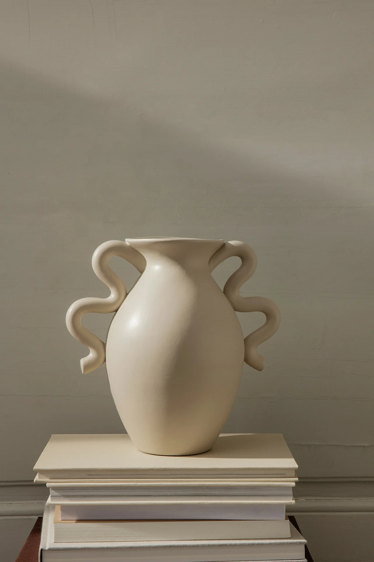 Beigefarbene Verso-Vase mit Wellenmuster von Ferm Living auf einem Bücherstapel.