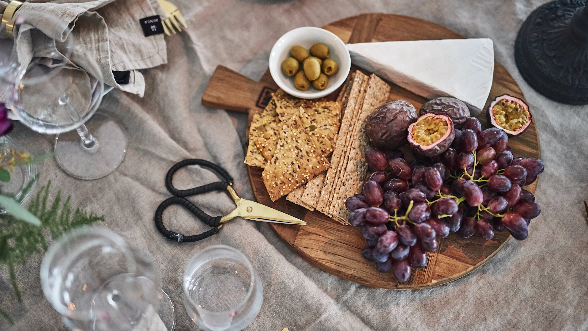 Auf dem Tisch steht ein Käsetablett, serviert auf einem runden Holzbrett.