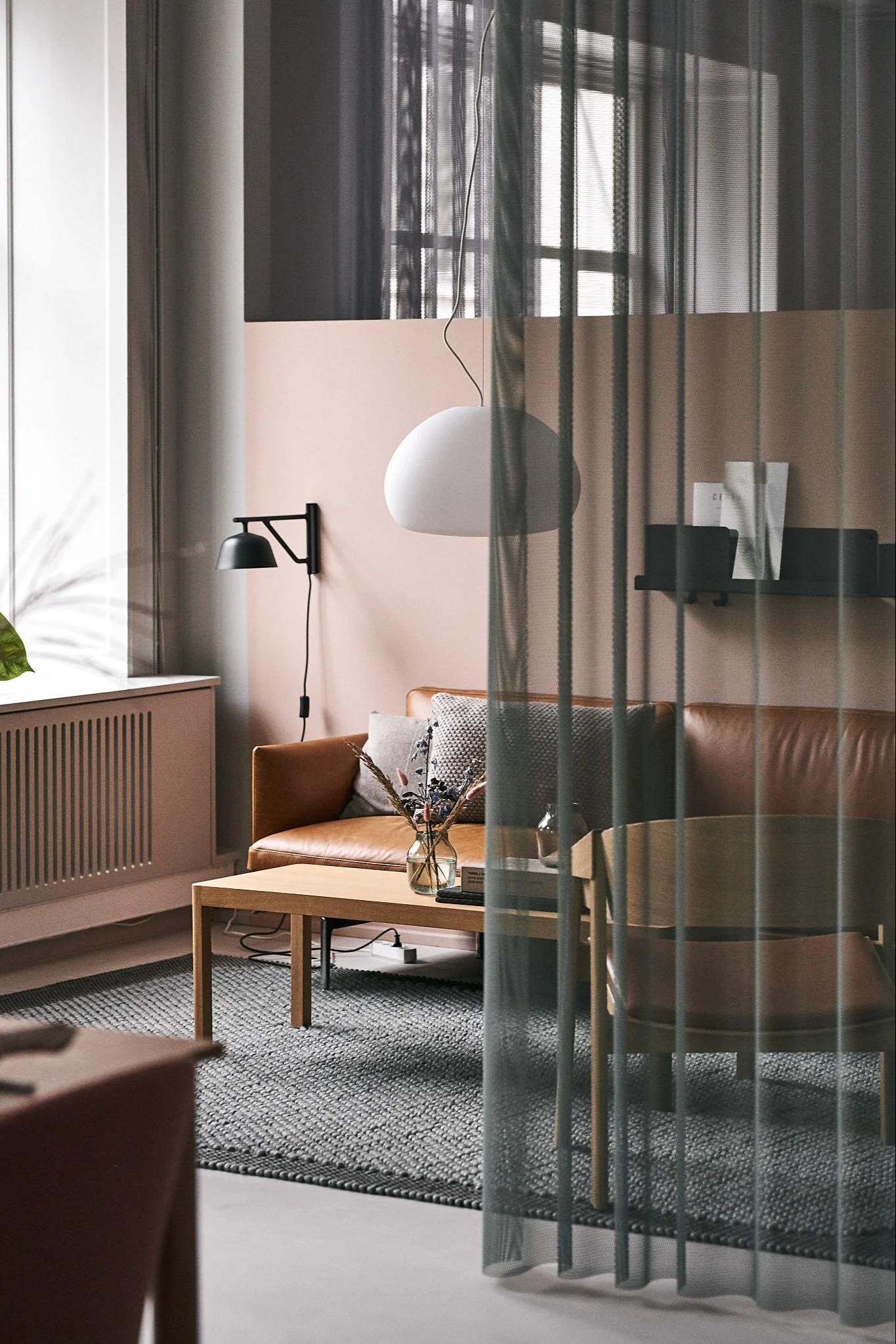 Das Wohnzimmer bei Muuto ist mit der Deckenleuchte Fluid und dem Ledersofa Outline eingerichtet. 