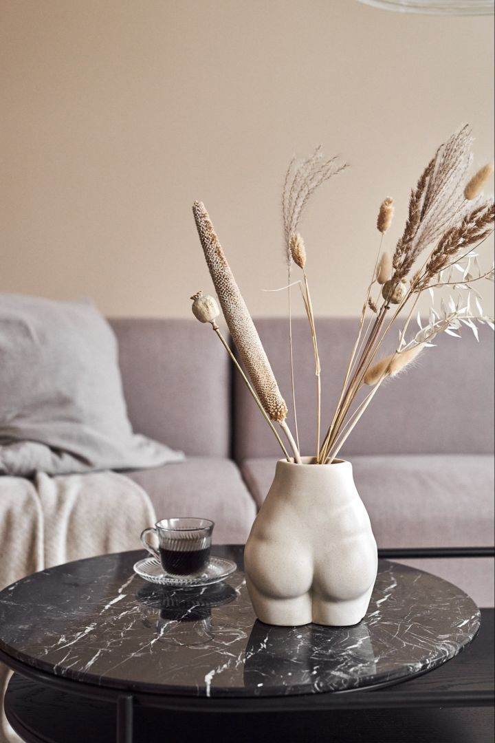 Richten Sie Ihr Wohnzimmer mit beigen Möbeln ein, um eine gemütliche Umgebung in Ihrem Zuhause zu schaffen. Hier sehen Sie die Vase Nature von By On, gefüllt mit wunderschönen Trockenblumen in denselben zarten Beigetönen.