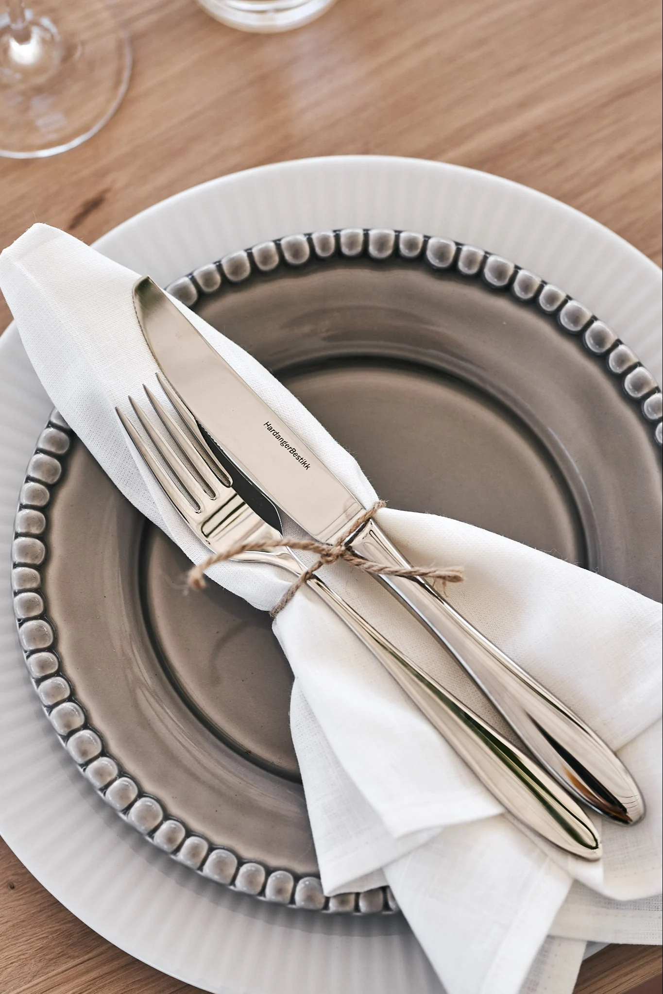 Leinenserviette in Weiß, zusammengebunden mit Besteck und Juteband.