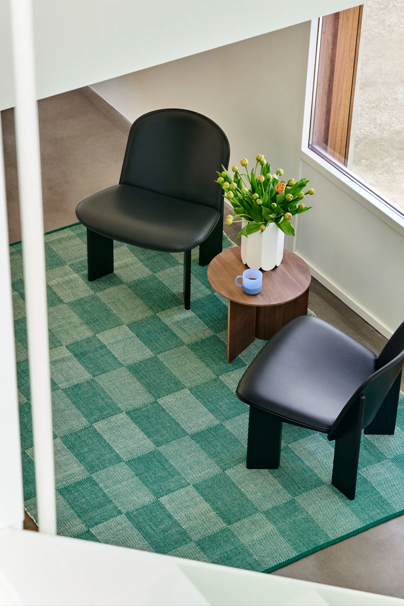 Wohntrends des Frühlings 2024: In den Einrichtungstrends für das Frühjahr 2024 sehen wir viele Muster, vorzugsweise kariert und gestreift in groß und klein. Hier sehen wir einen grünen und karierten Teppich von HAY in einer Wohnzimmerumgebung, ein Einrichtungsdetail, das auffällt und einen Blickfang im Raum schafft.