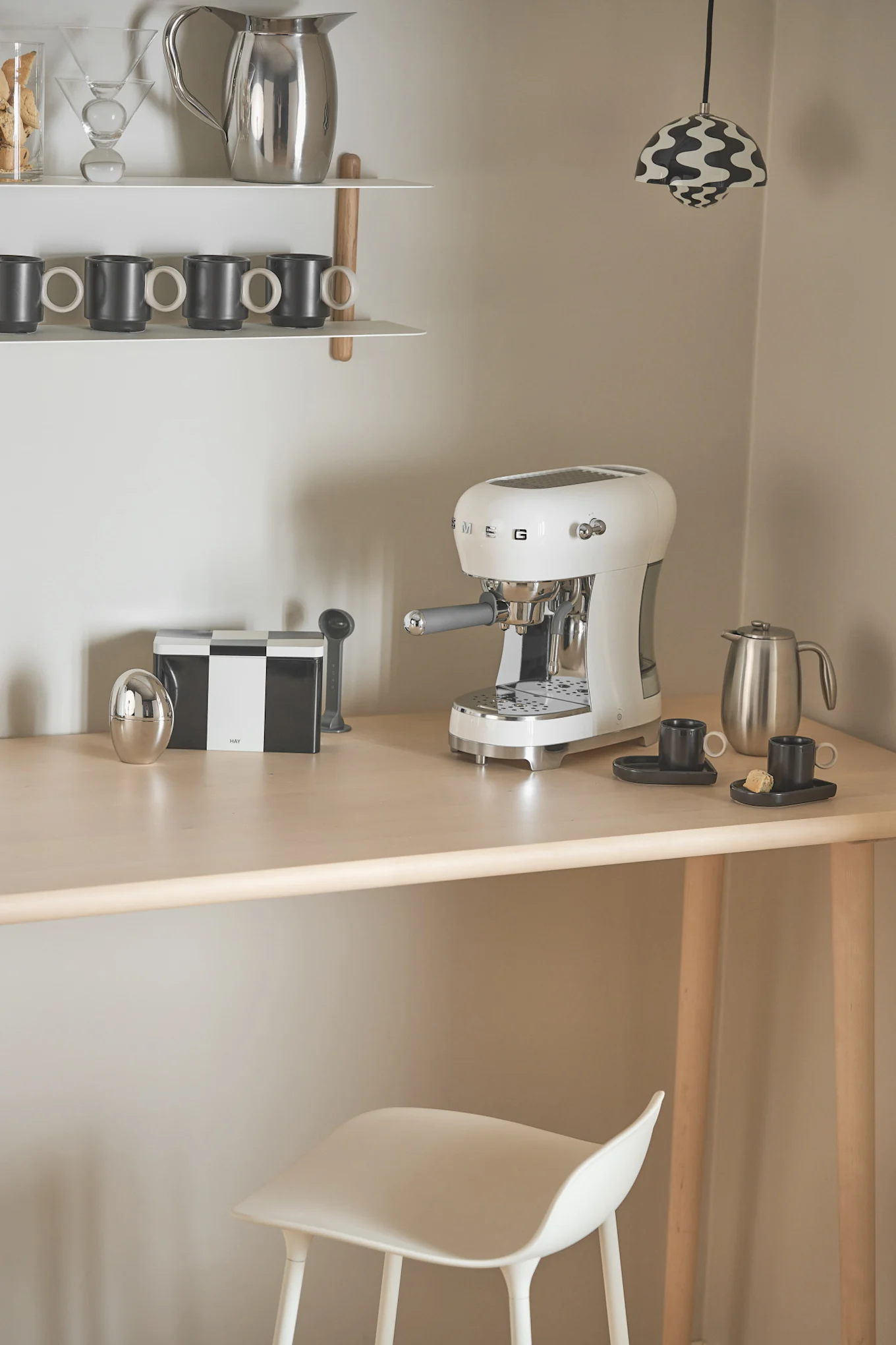 Für eine Kaffeebar zu Hause eignet sich die Kaffeemaschine von Smeg ganz besonders gut, welche Sie hier in einer Ecke stehen sehen, als Beleuchtung fungiert eine Flowerpot-Pendelleuchte von &tradition.