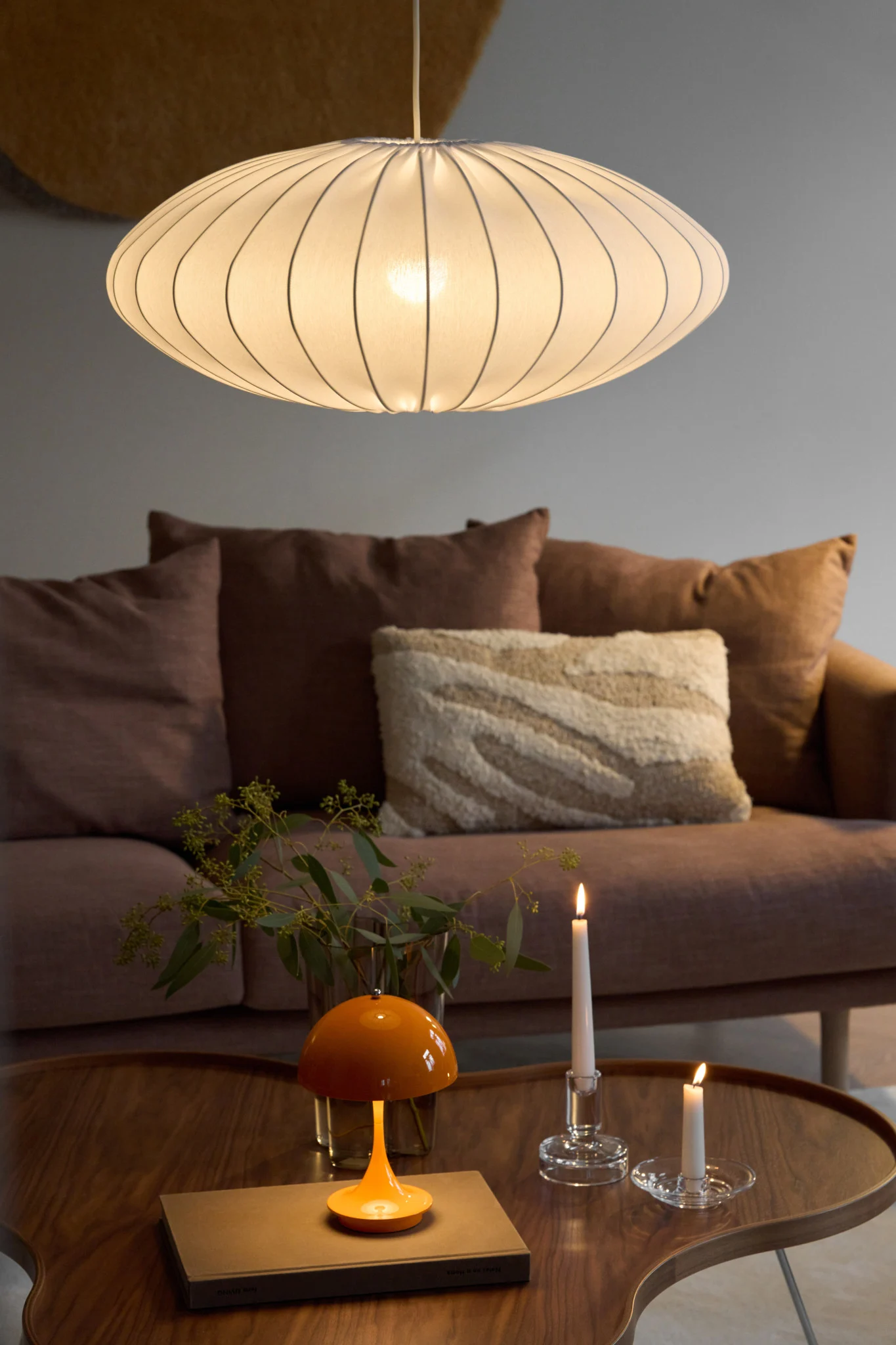 Die Ellipse-Pendelleuchte mit Stoff-Lampenschirm von Watt & Veke hängt in einem gemütlich eingerichteten Wohnzimmer.