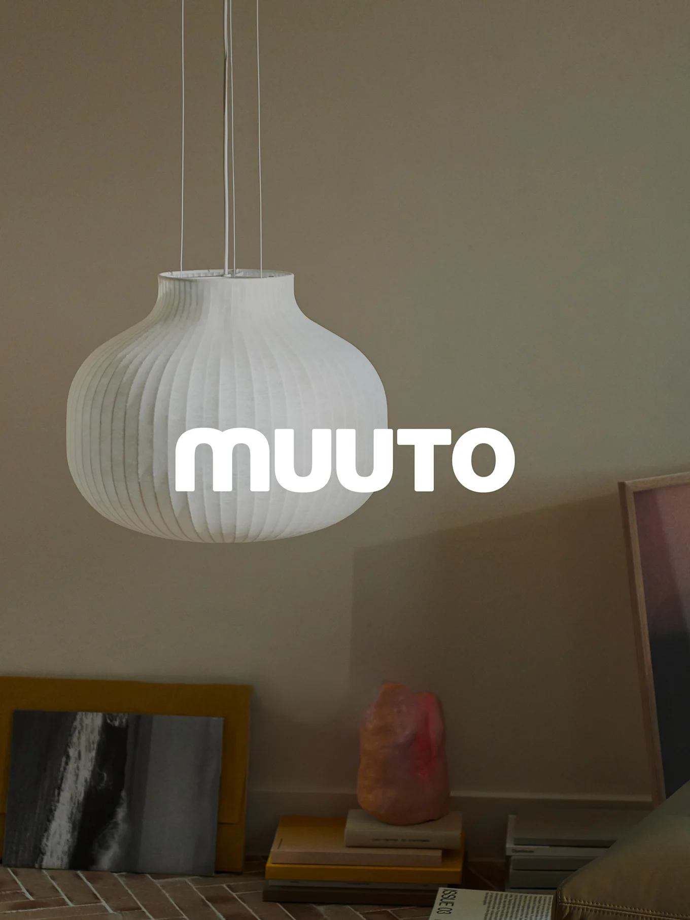 Weiße gerippte, kürbisförmige Pendelleuchte mit 'MUUUTO'-Logo in einem beigen Raum.