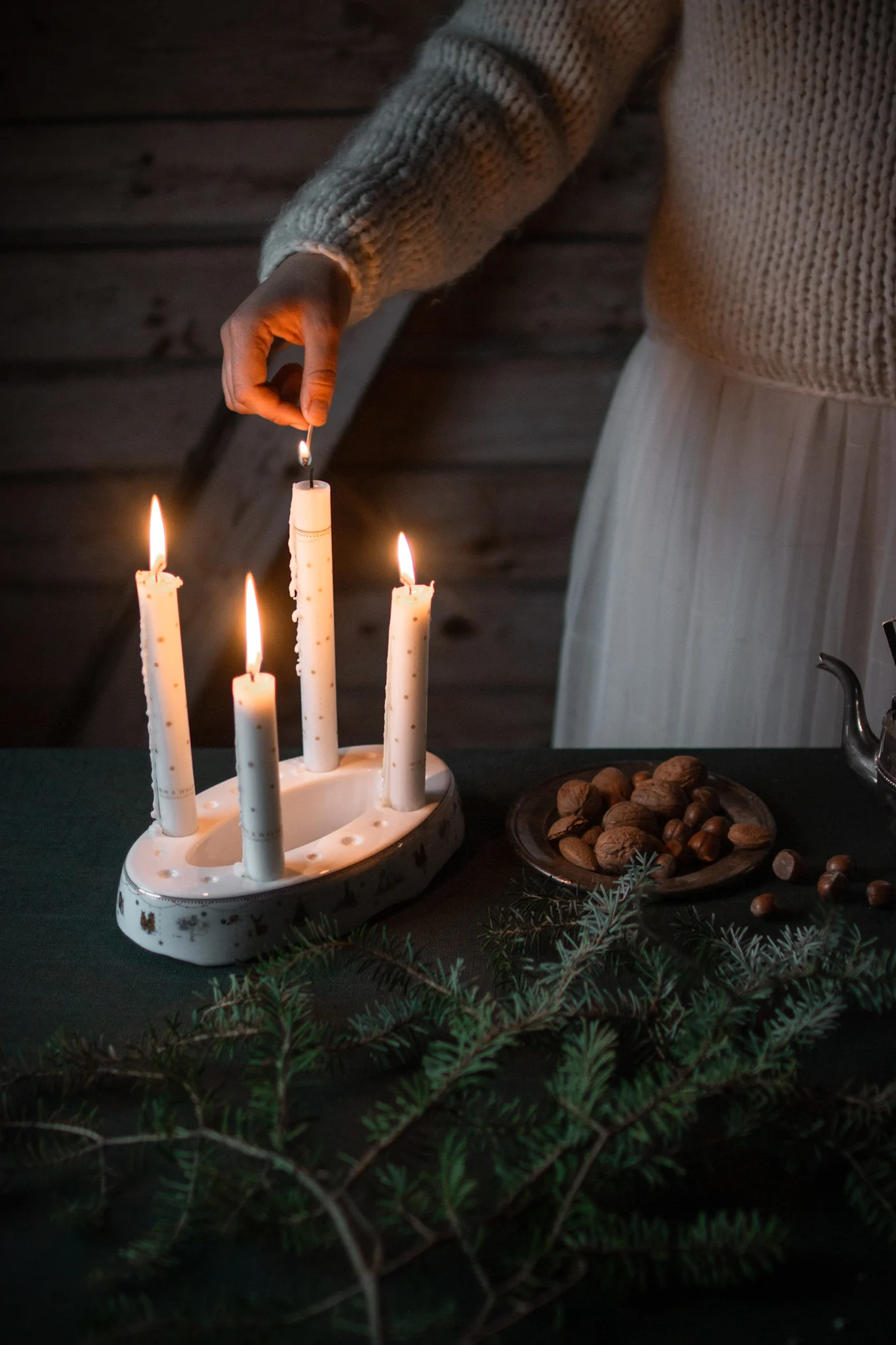Der Julemorgen Story Kerzenhalter von Wik & Walsøe steht auf einem weihnachtlich mit Tannengrün dekorierten Tisch.