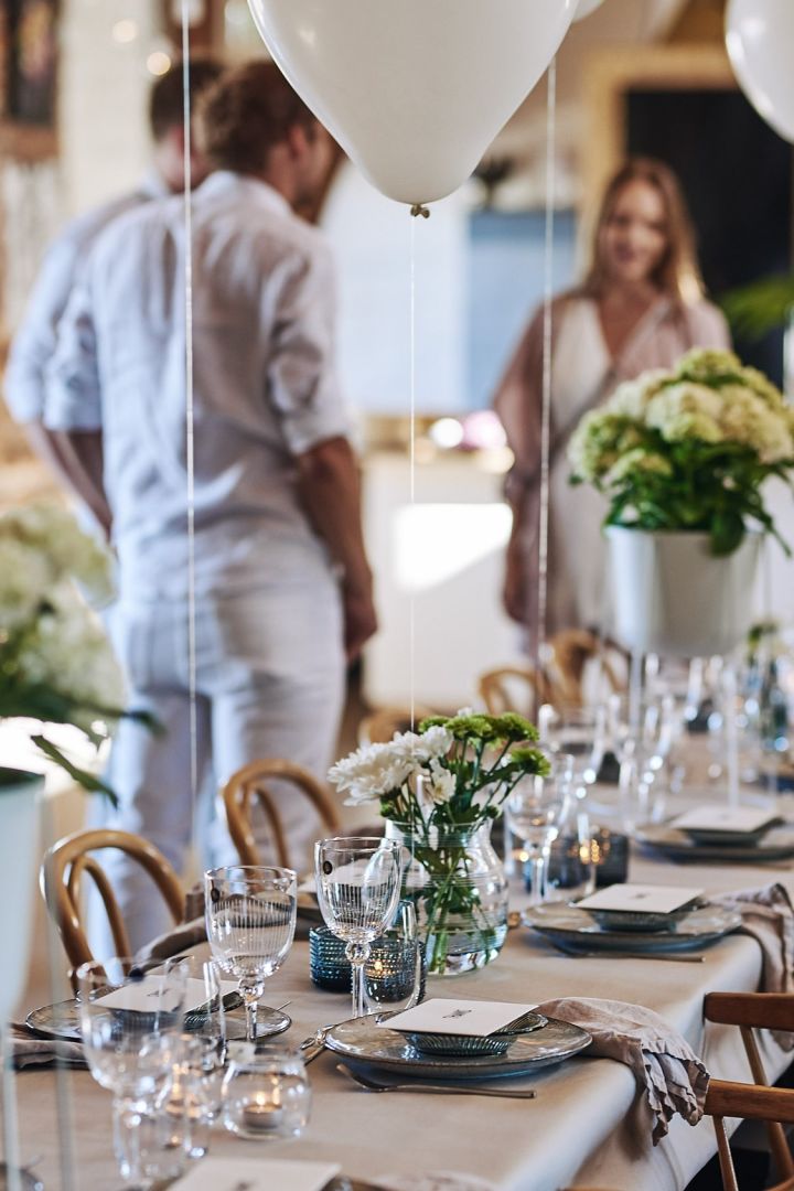 Mit langen Tischen und stilvoll gedeckten Tischen in kühlen Tönen ist der Tisch bei diesem Sommerfest in Weiß dekoriert. 