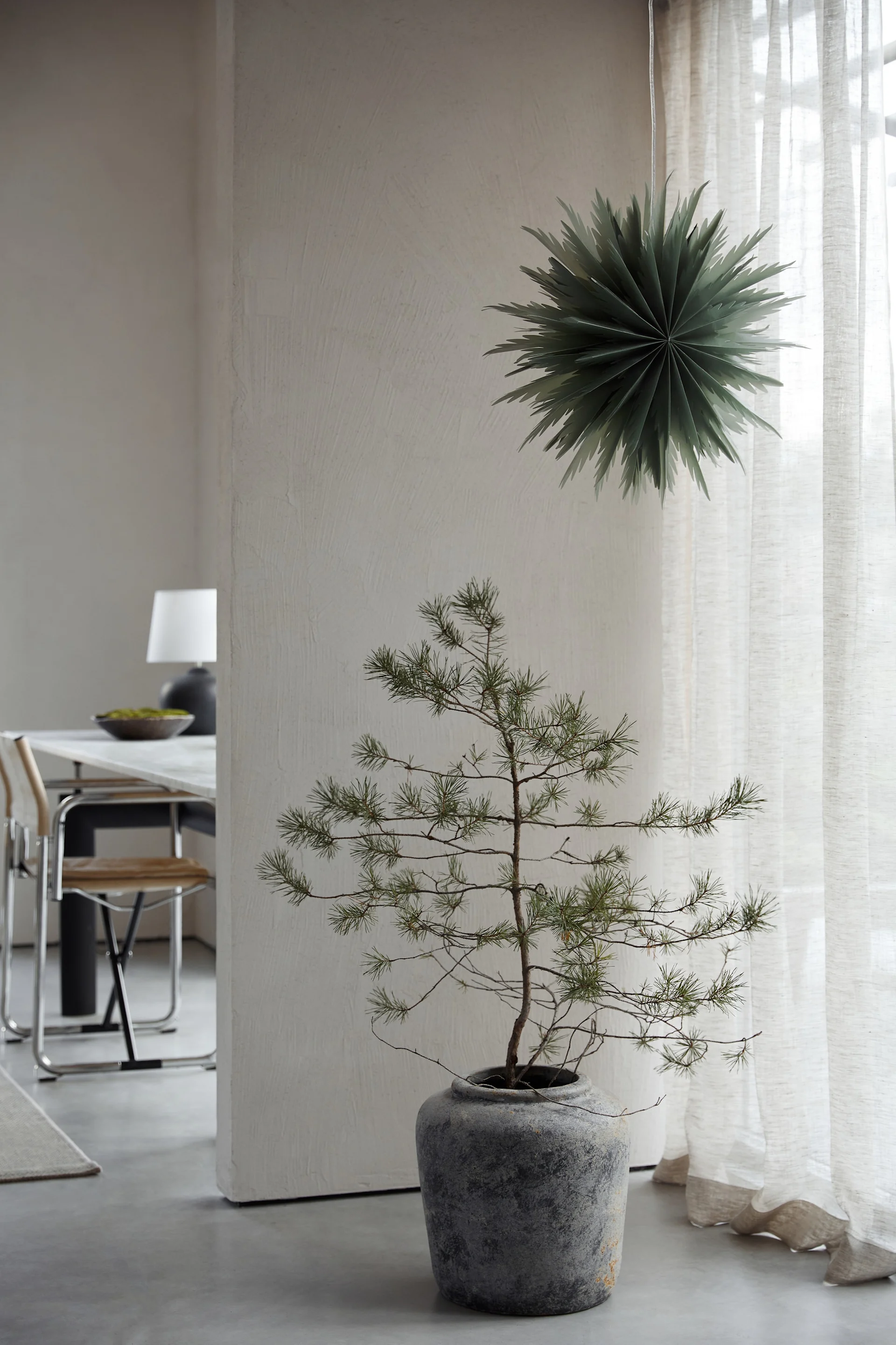 Weihnachtsdeko modern wie der Oslo-Weihnachtsstern aus Papier von Watt & Veke. Hier zu sehen, wie er im Fenster eines Wohnzimmers in neutralen Farben hängt. 