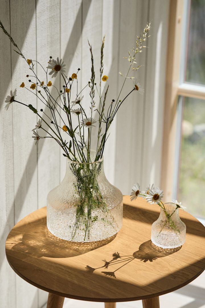 Die beste Vase für kleine Sträuße und einzelne Blumen ist eine kleine oder eine Mini-Vase wie die Ultima Thule-Vasen, die Sie hier im Sonnenschein auf einem Tisch sehen. 