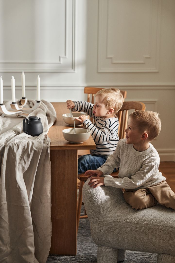 Zwei kleine Jungs sitzen an einem Tisch von Design House Stockholm. Das Foto zeigt zudem den Lulu Pouf und die Schüsseln der NM&Sand-Serie.