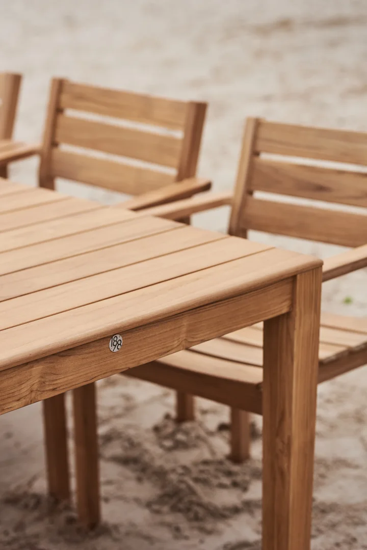 Hölzerner Gartentisch mit Stühlen auf Sand, mit einer '188' Plakette.