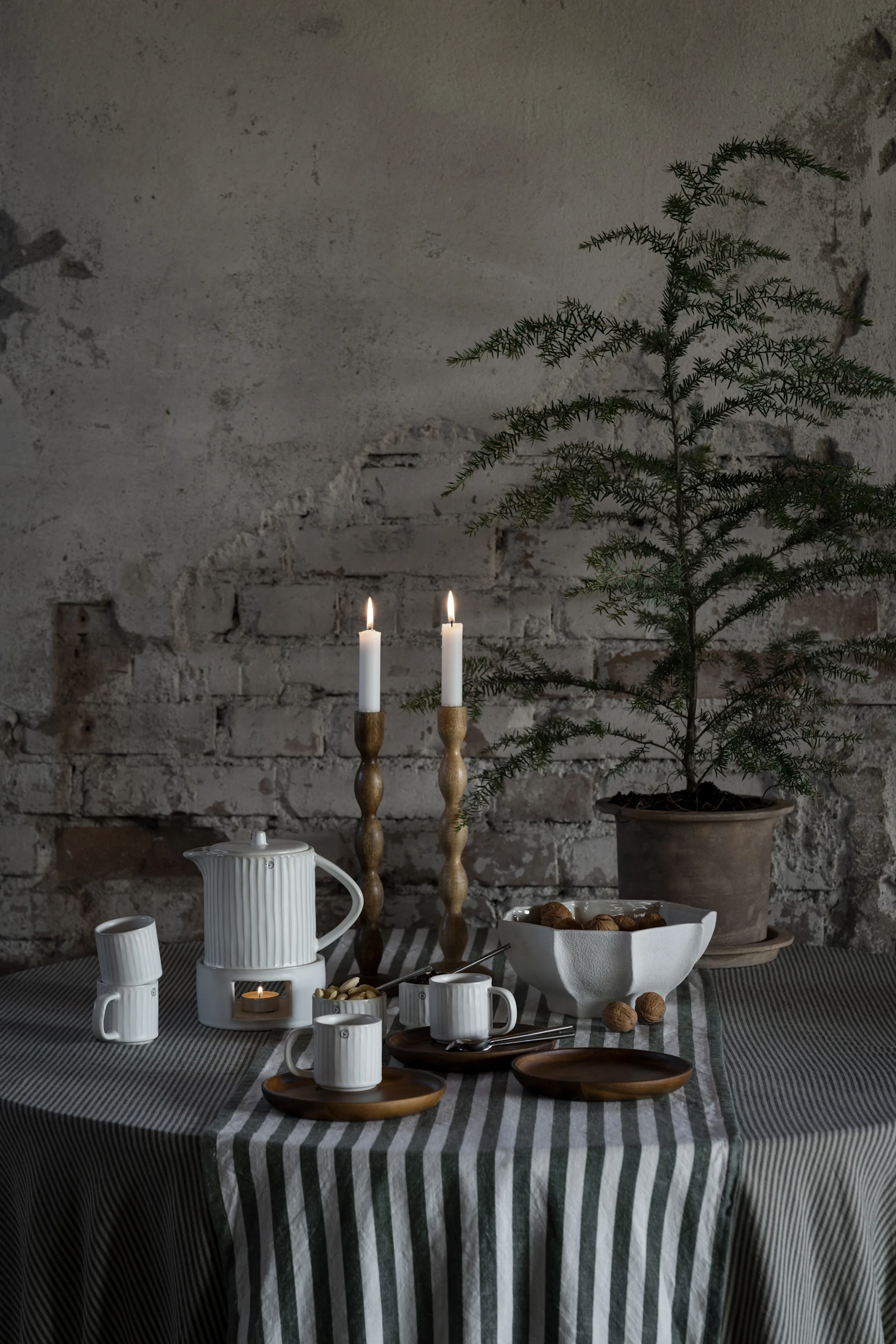 Ein gedeckter Tisch mit Geschirr, Kanne, Kerzenhaltern und der grün-weiß gestreiften Tischdecke von Ernst.