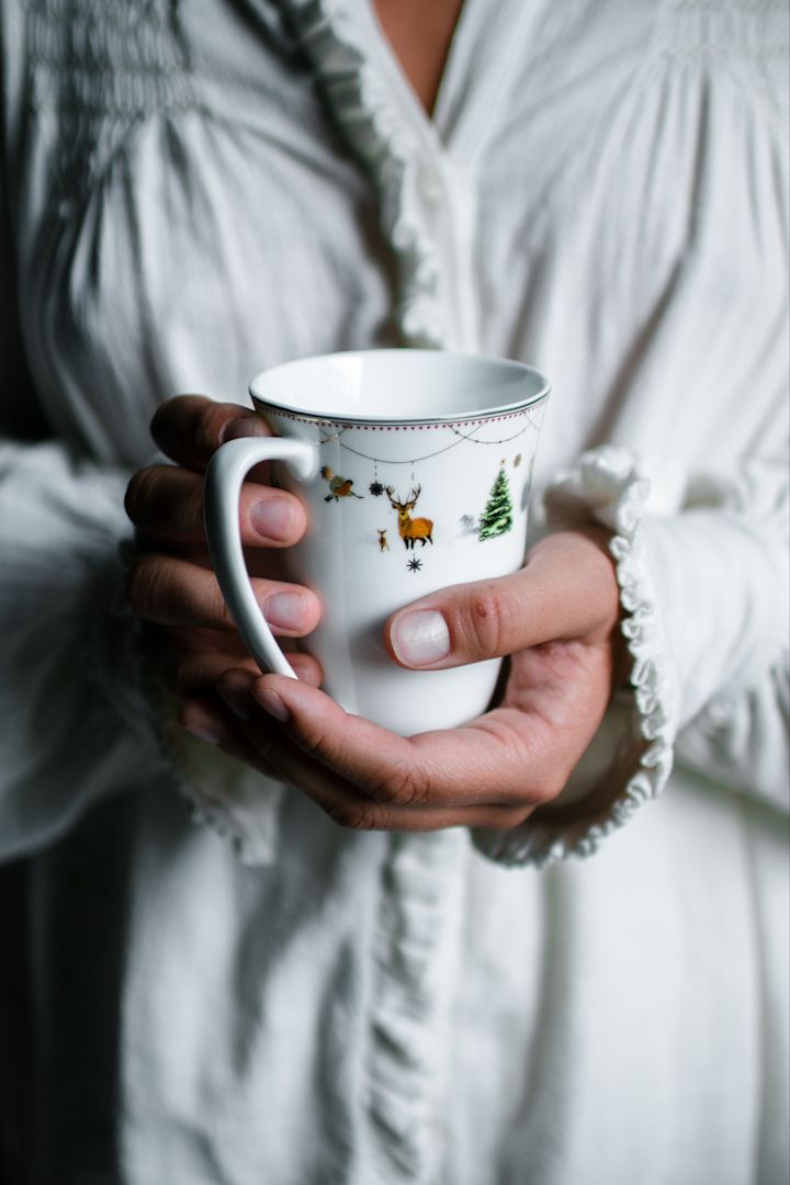 Hier sehen Sie eine Person, welche sich die Hände an der Julemorgon-Tasse von Wik & Walsøe wärmt.