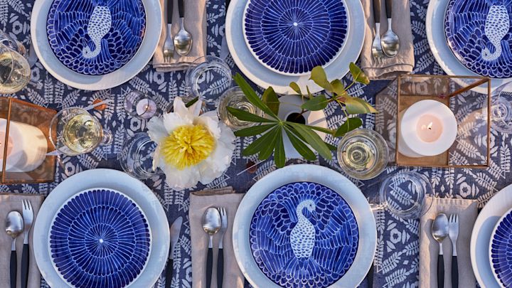 Decken Sie den Tisch für Mittsommer im Bohème-Stil mit blauem und weißem Porzellan von Götefors Porzellan, Retro-Besteck von Gense und Kerzenlaternen auf dem Tisch.