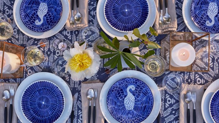 Decken Sie den Tisch für Mittsommer im Bohème-Stil mit blauem und weißem Porzellan von Götefors Porzellan, Retro-Besteck von Gense und Kerzenlaternen auf dem Tisch.