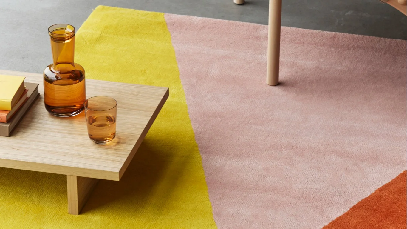 Ein Wohnzimmer, ausgestattet mit einem beigefarbenen Teppich und einer grünen Wolldecke  aus der NJRD-Kollektion.