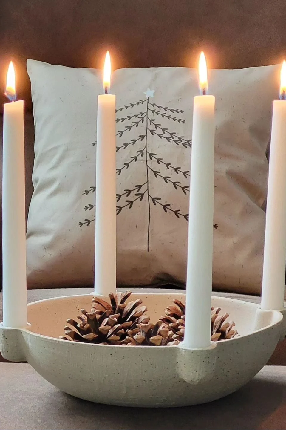 Ein mit Zapfen dekorierter Bowl Adventskerzenhalter von Ferm Living.