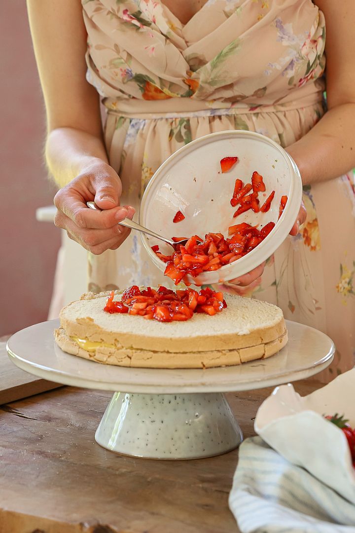 Für die schwedische Erdbeertorte werden Erdbeeren auf dem Baiserboden verteilt.
