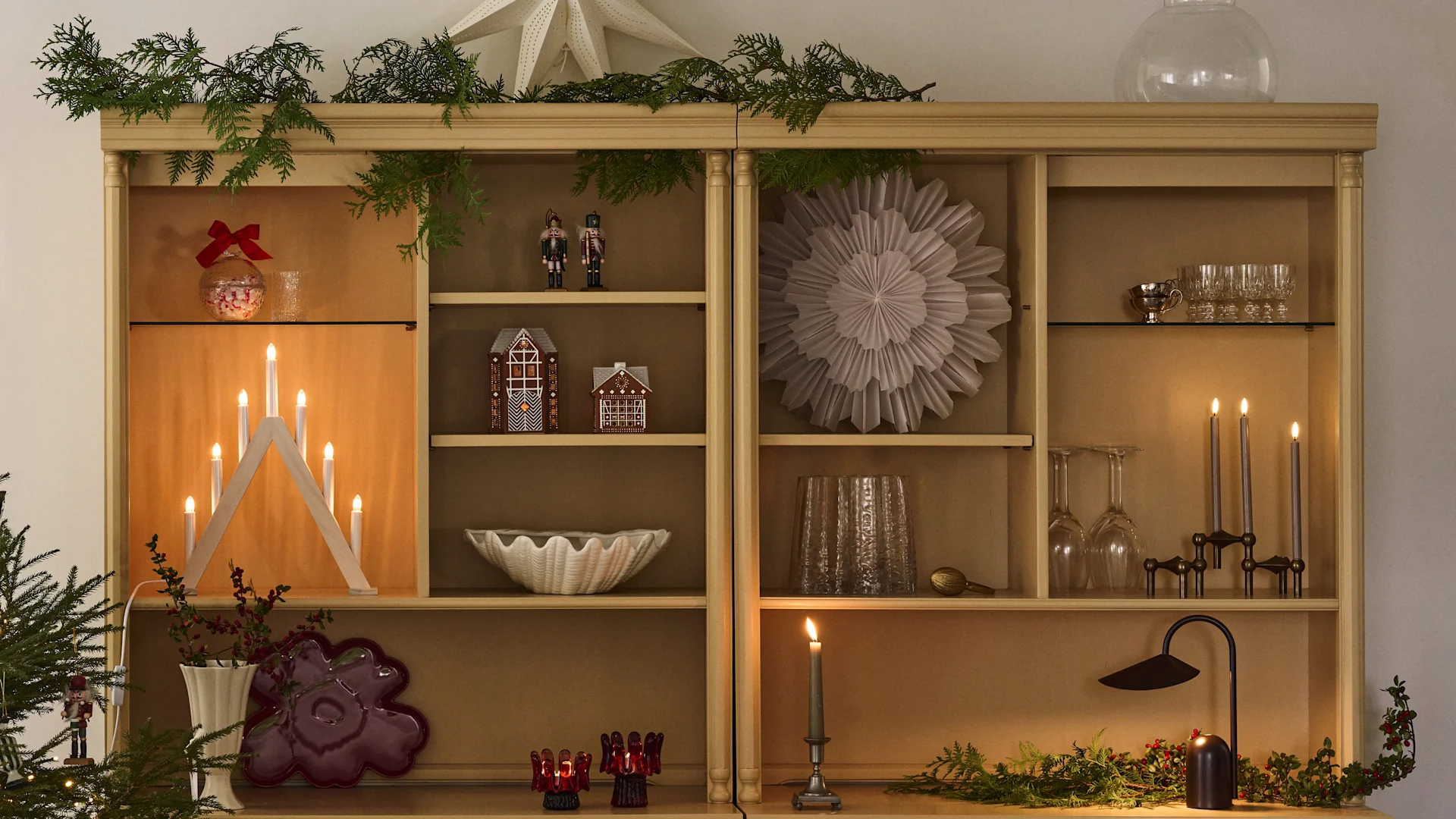 Weihnachtlich dekoriertes Bücherregal mit Weihnachtssternen und Kerzenständer, perfekt, um sich auf den ersten Advent einzustimmen.