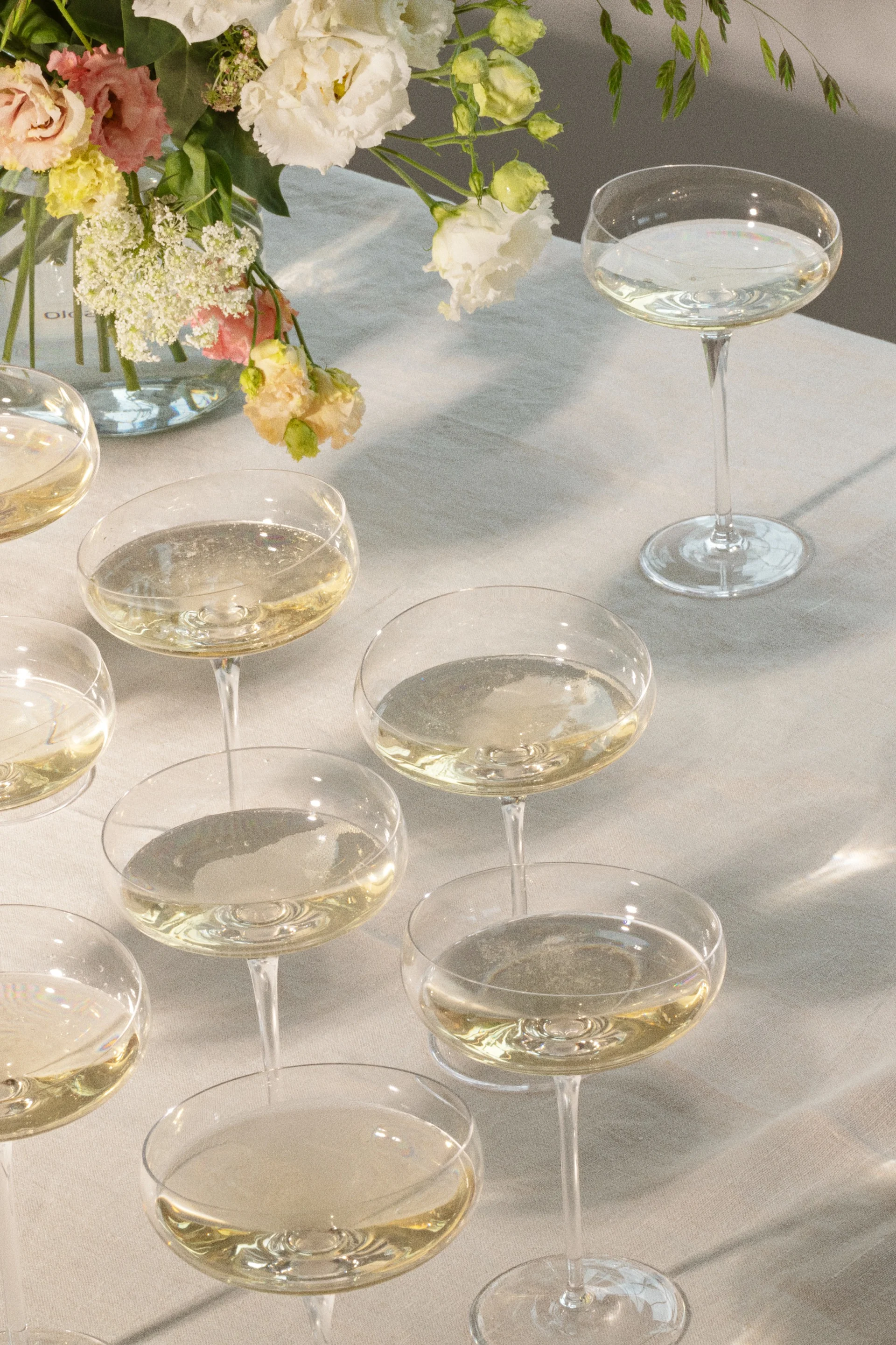 Sektgläser mit Schaumwein auf einem Tisch mit Blumenarrangement.