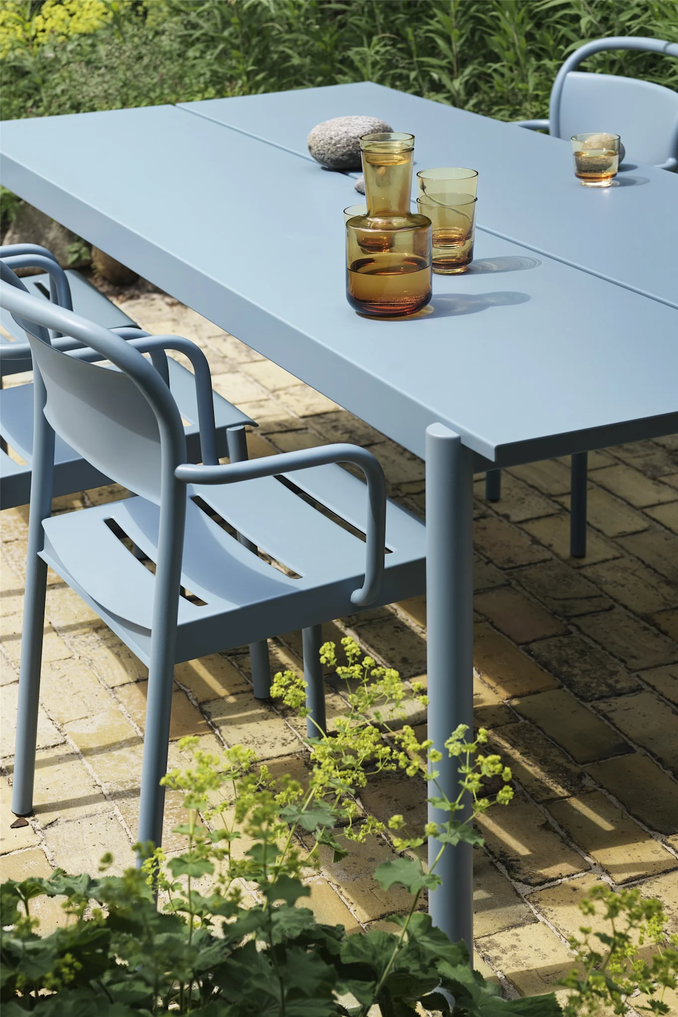 Der Stuhl aus der Linear-Kollektion in Pale Blue von Muuto steht hier am dazugehörigen Tisch und besticht mit seiner sanften, abgerundeten Form und ist somit absolut im Trend, was Gartenmöbel 2025 angeht.
