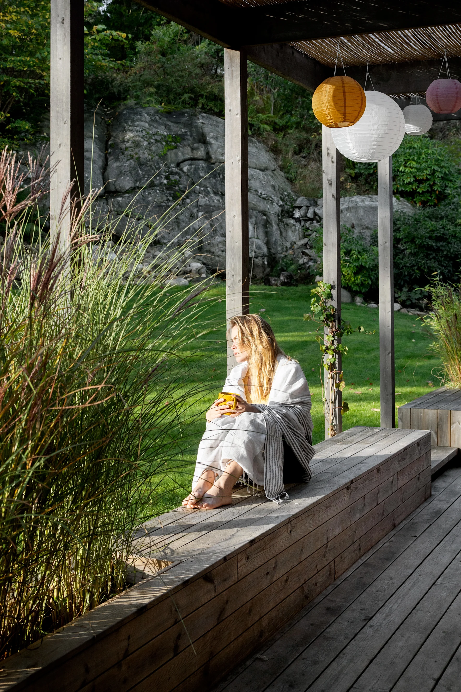 Nehmen Sie sich Zeit für Ihre Fika und genießen Sie sie an einem ruhigen Ort in der Natur, wie diese Frau, die auf einer Terrasse sitzt und ins Grüne blickt.