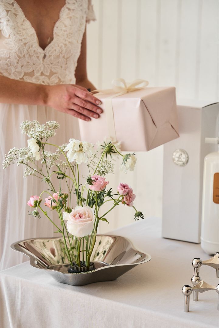 Hier sehen Sie die Alvar Aalto-Schale aus Edelstahl als Vase auf einem Hochzeitstisch. Versuchen Sie diese besondere Idee für Ihren Hochzeitstag. 