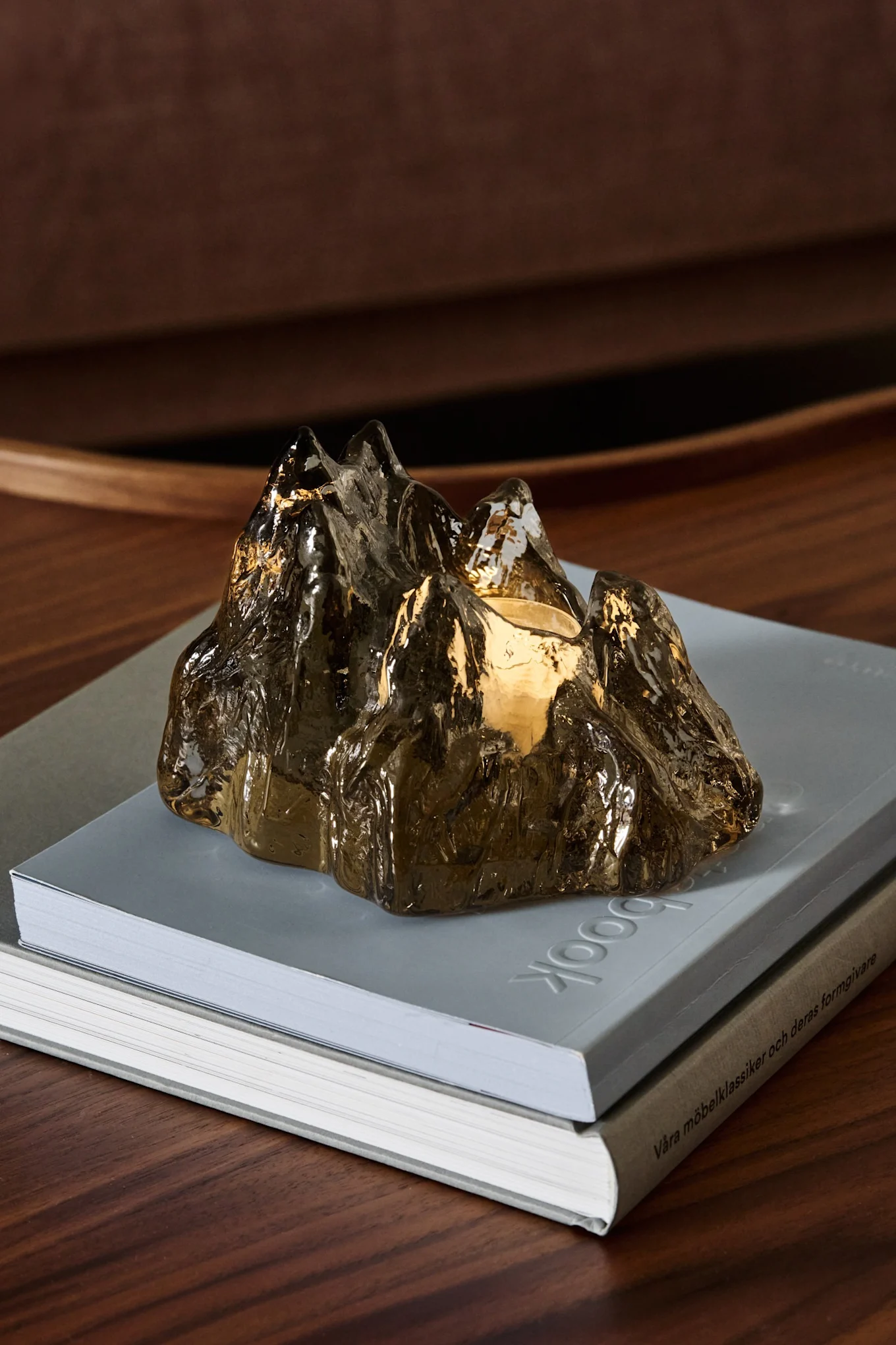 Auf einem Nordic Nest-Paket steht der braune The Rock-Kerzenhalter von Kosta Boda unter einem Weihnachtsbaum.