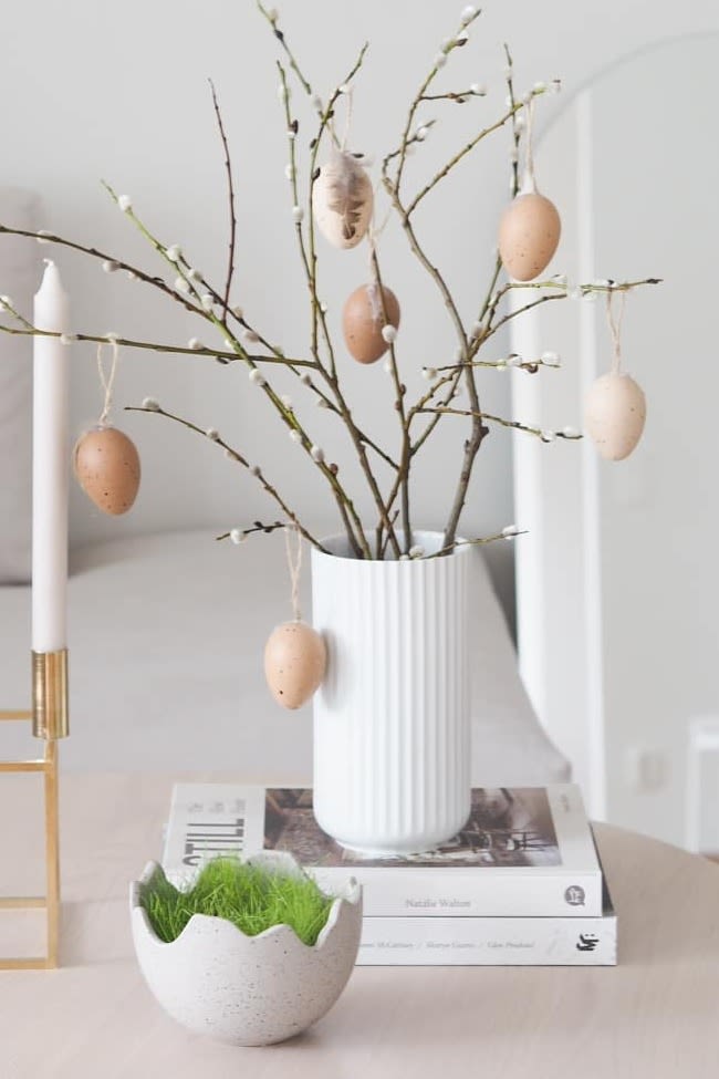 Osterdekoration: Hier sehen Sie die Osterdekoration des Instagram-Profils @arkeniestetiikkaa, welche aus dem Kubus Kerzenhalter von Audo Copenhagen, der Happy Easter Schale und der Lyngby Vase in Weiß mit frühlingshaften Zweigen darin.