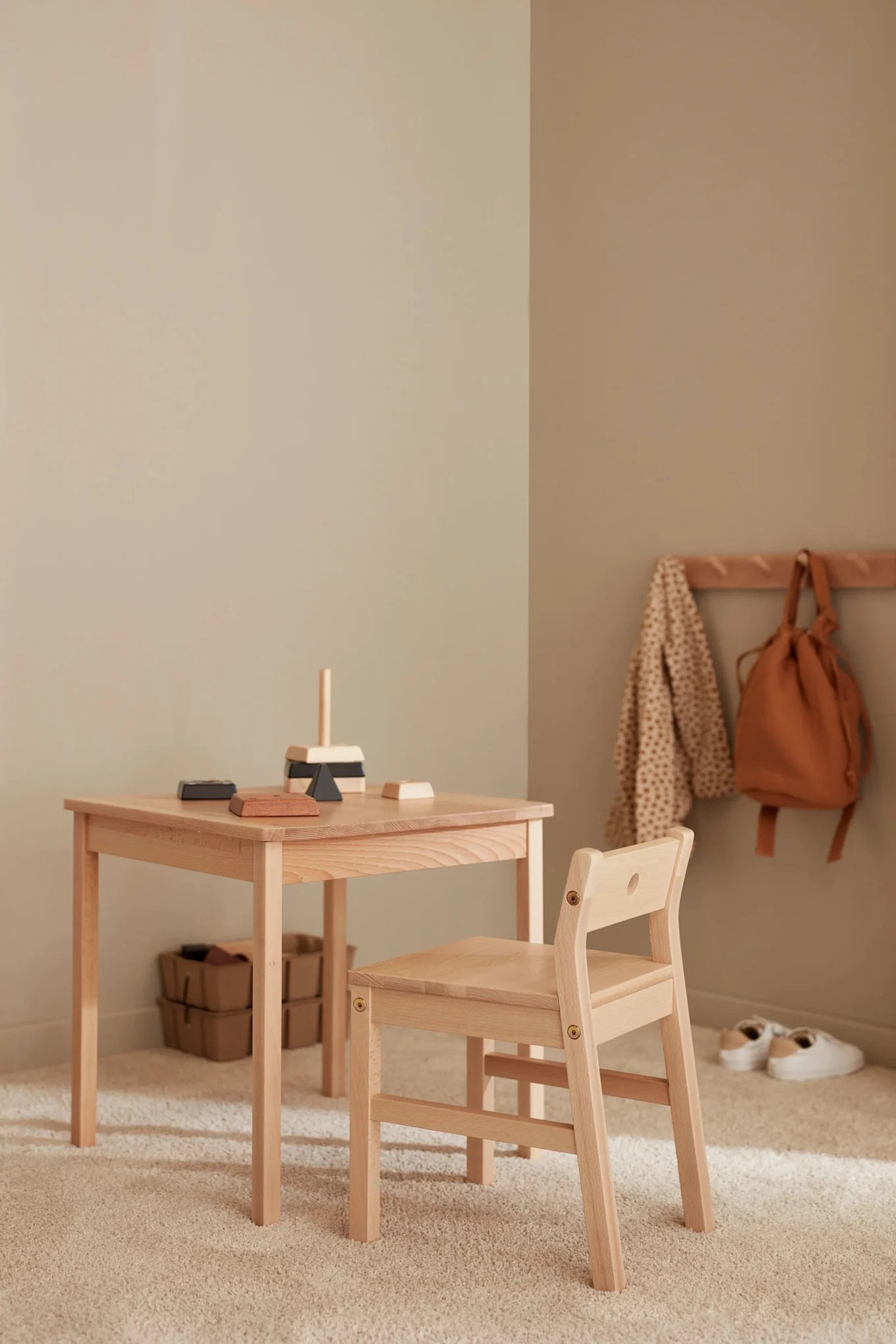 Der Saga-Tisch und die Stühle aus Holz stehen in einem farblich neutralen Kinderzimmer. 