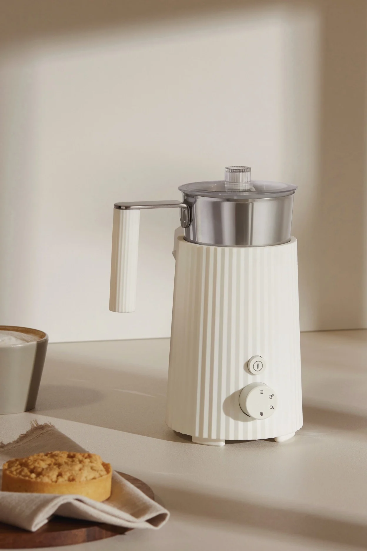 Der weiße Plissé Milchaufschäumer von Alessi steht auf einer Anrichte - die perfekte Hochzeitsgeschenk-Idee für Kaffeeliebhaber.