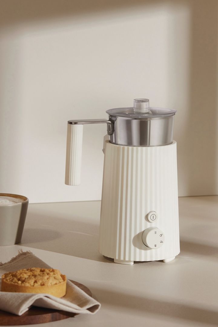 Der weiße Plissé Milchaufschäumer von Alessi steht auf einer Anrichte - die perfekte Hochzeitsgeschenk-Idee für Kaffeeliebhaber.