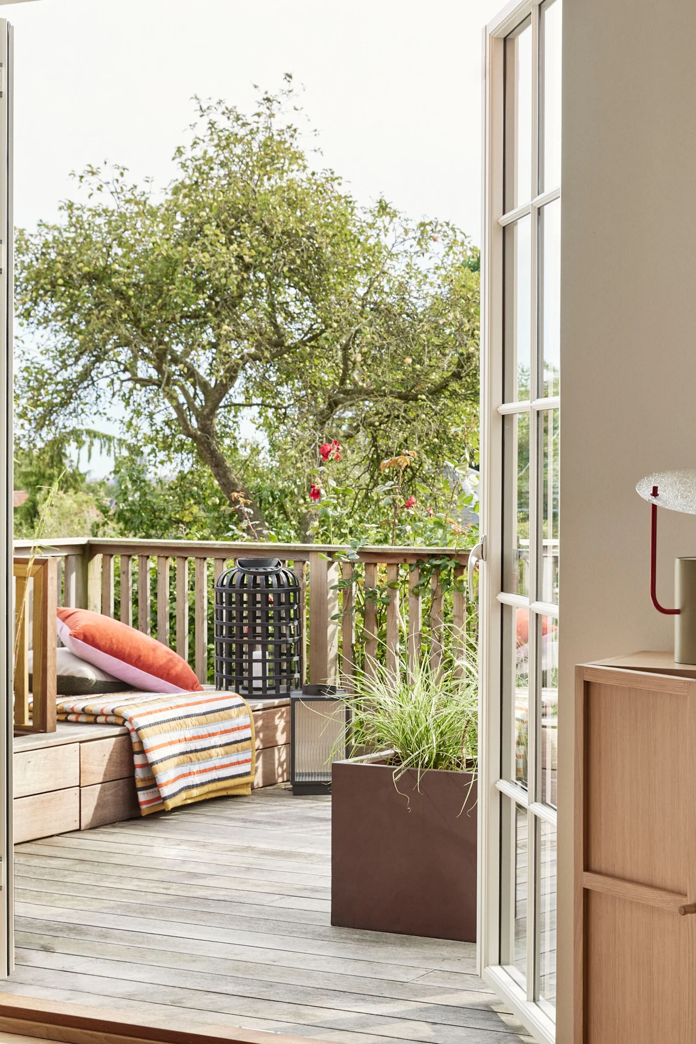 Boho-Balkon dekorieren: Die gestreifte Decke von Hübsch Interior liegt auf einem hölzernen Balkon.