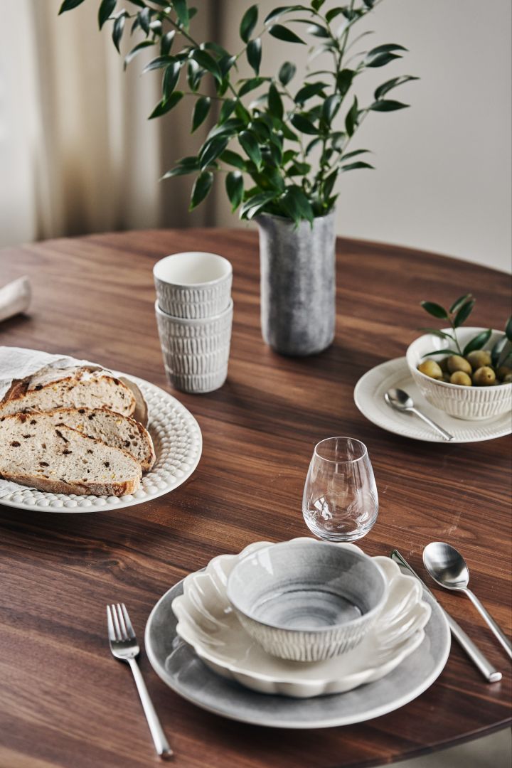 Et dekket bord med grå og beige tallerkener, skåler, kopper, fat og kanne fra Mateus-serien Bubbles, Stripes, MSY, Basic og Oyster.