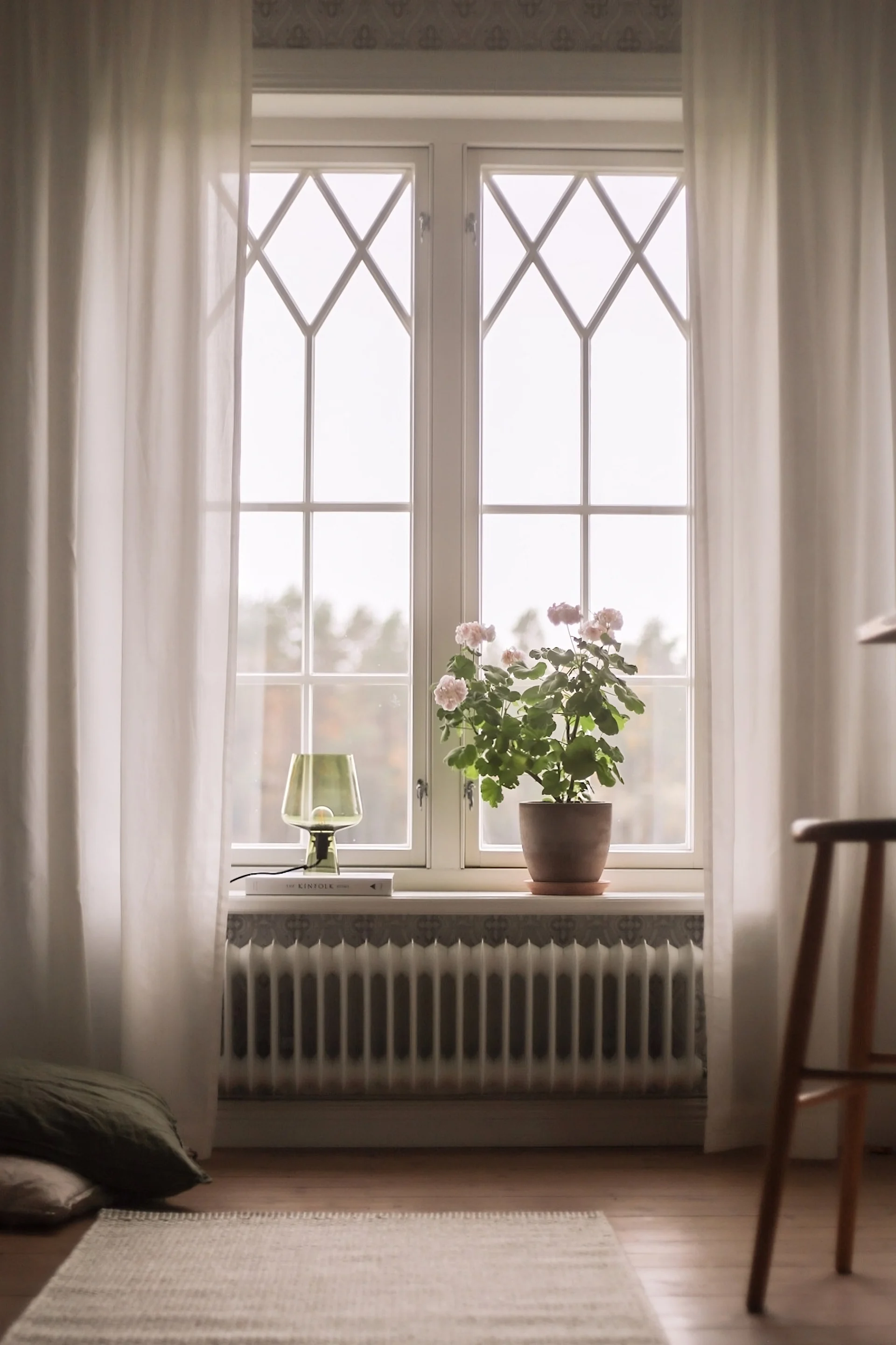 Dekorieren Sie die Fensterbank mit einer Blume im Topf und der Leimu Tischlampe von Iittala auf einem kleinen Bücherstapel.