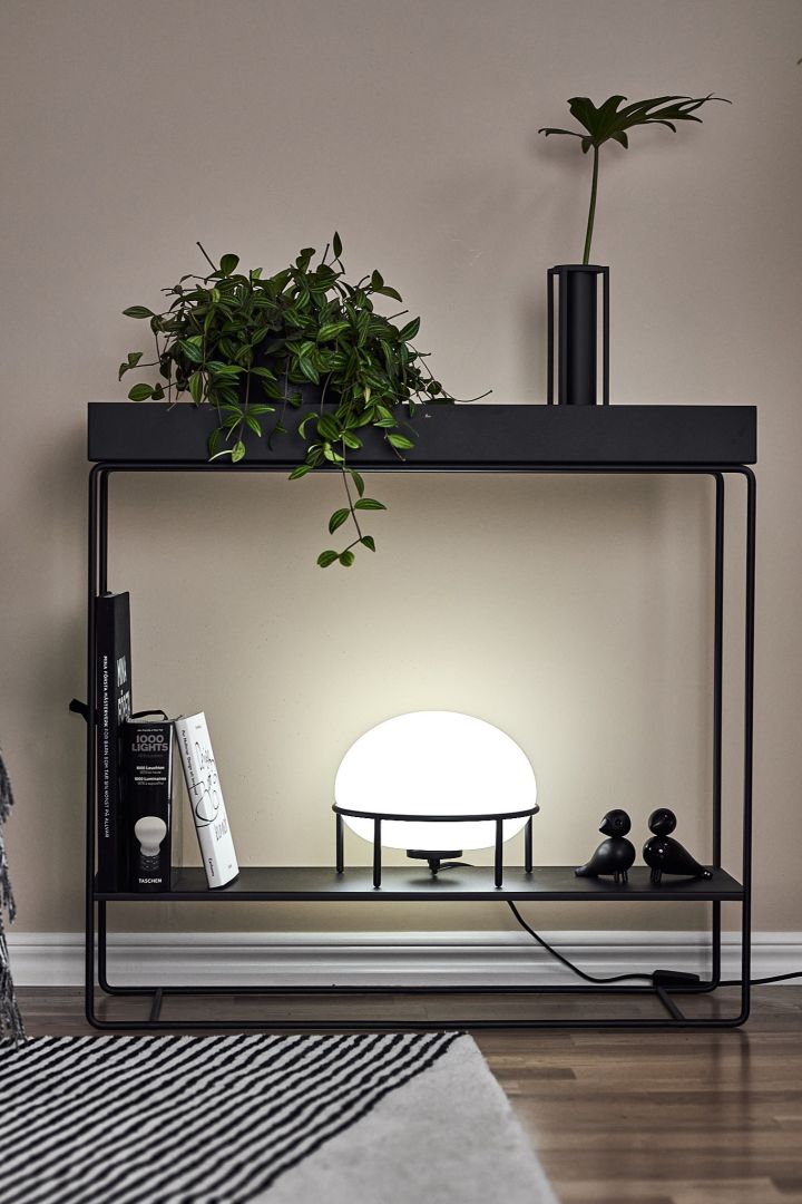 Grafisches Schwarz-weiß gestaltetes Wohnzimmer mit minimalistischen Möbeln,klaren Linien, grünen Pflanzen und einer runden Tischlampe.