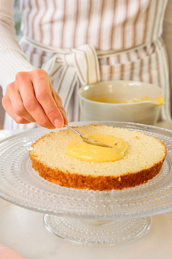 Schokodesserts für Silvester von Baka med Frida: Verstreichen Sie die Maracuja-Masse auf dem unteren Tortenboden, welcher hier auf der Kuchenplatte aus der Kastehelmi-Kollektion von Iittala liegt.