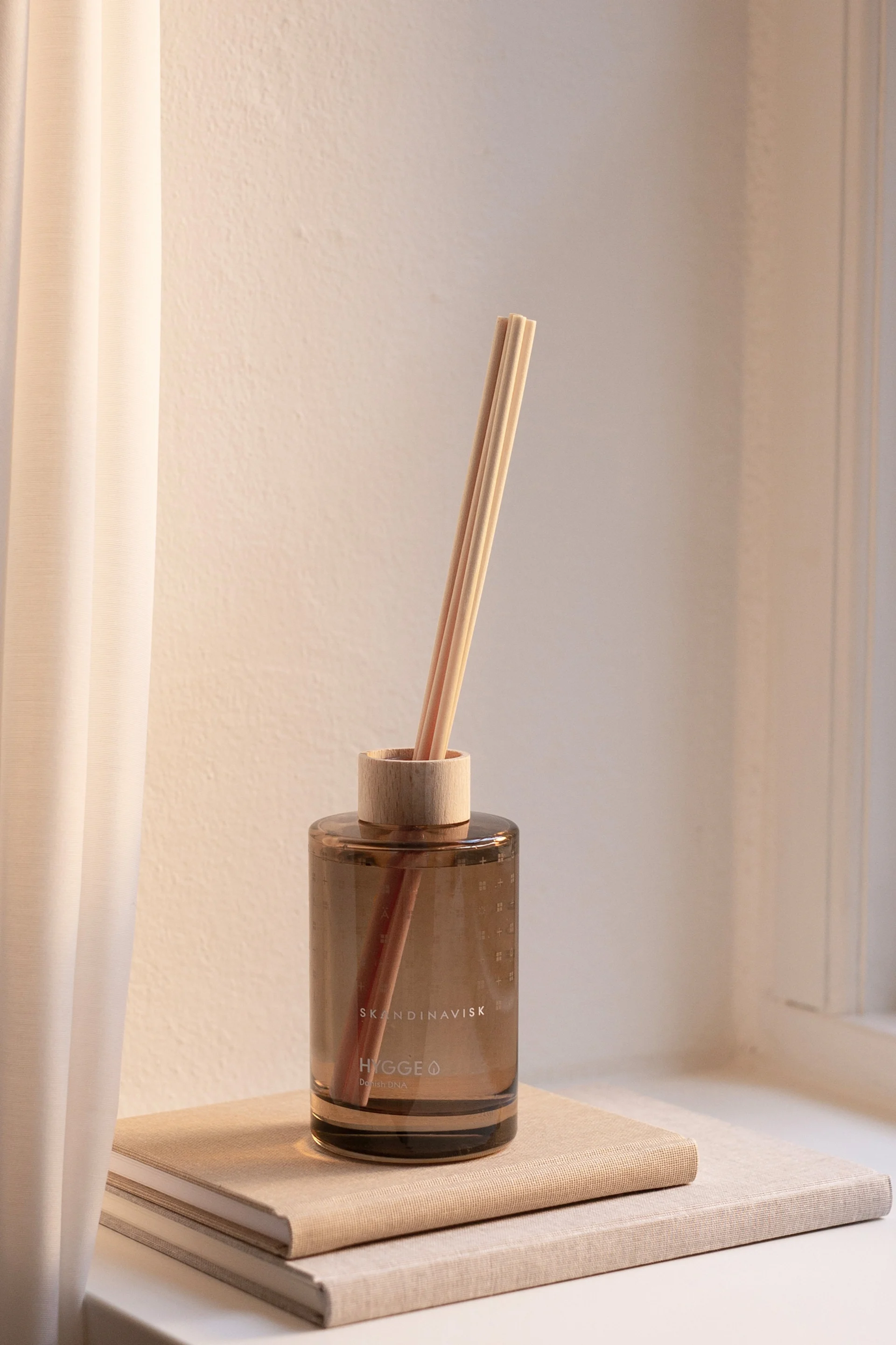 Auch ein angenehmer Geruch gehört zu einem Feng Shui Schlafzimmer. Hier stehen die Hygge Duftstäbchen von Skandinavisk auf zwei Büchern auf einem Fensterbrett.