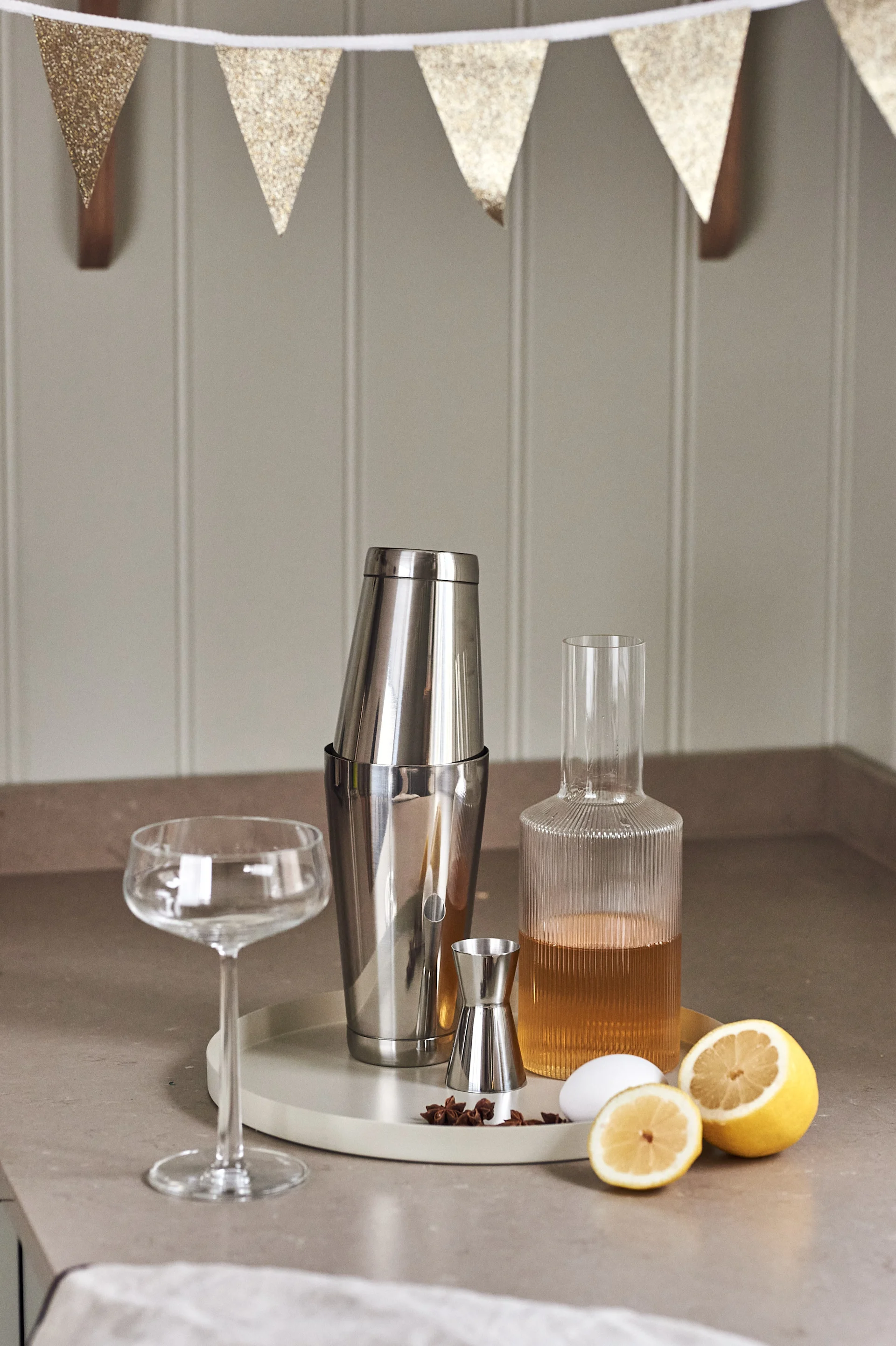 4 Cocktailrezepte für besondere Anlässe – ein gelungenes Fest. Hier der Dorre Cocktailshaker, der Rosendahl Messbecher und die Ripple Karaffe von Ferm Living auf einem Tablett von Cooee Design.