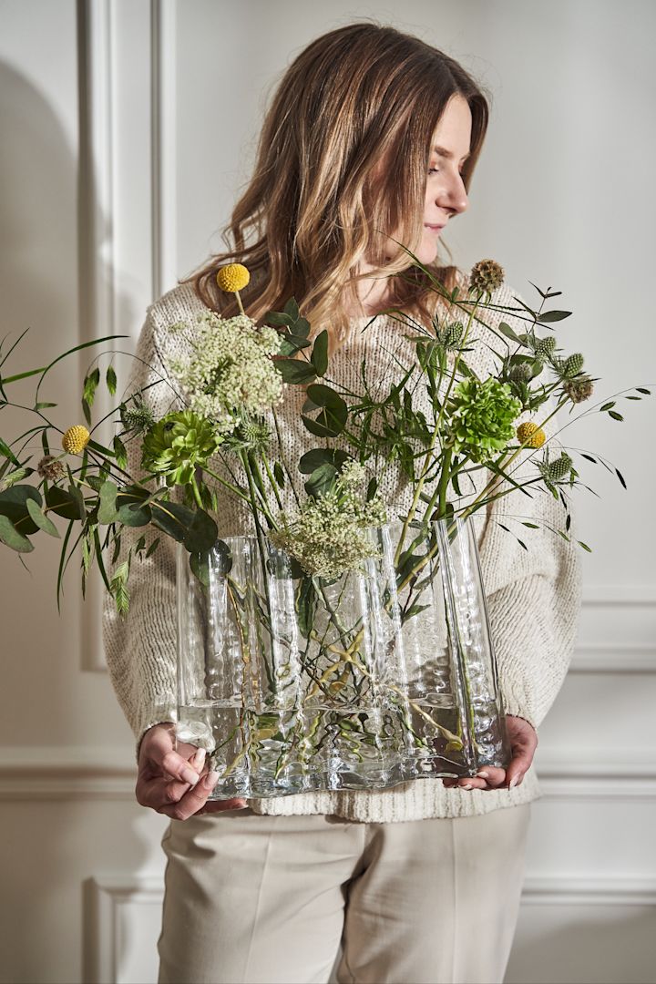 Eine runde durchsichtige Vase mit Blumen auf einem Marmortisch.