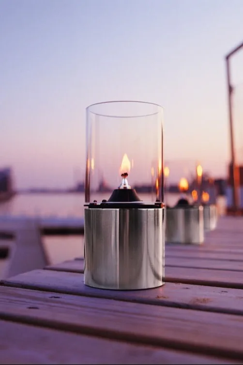Platzieren Sie Laternen und Windlichter für draußen auf Ihrem Balkon, auf der Terrasse oder im Garten, beispielsweise die stilvolle Ölleuchte von Stelton.