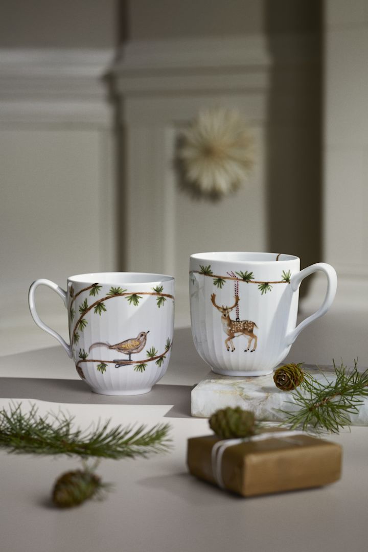 Zwei weihnachtliche Tassen aus der Hammershøi Christmas-Kollektion von Kähler stehen auf einem Tisch und sind eine wunderbare skandianvische Weihnachtsdeko.